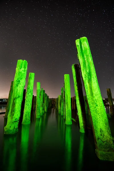 Unusual poles in the water at night on a background stars — Stock Photo, Image