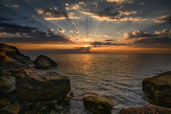 Schöner Sonnenaufgang über dem Meer - ruhiges Meer und Felsbrocken mit Himmelssonne — Stockfoto