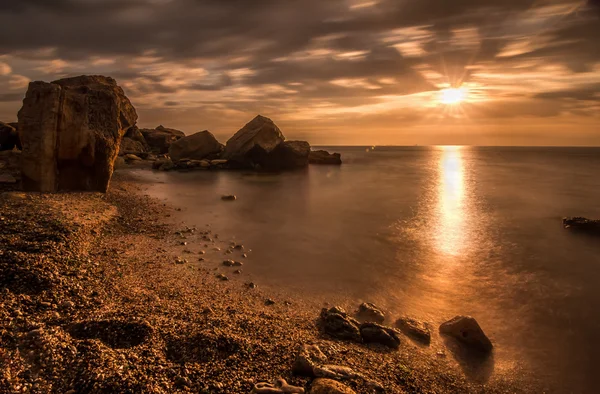 Hermosa salida del sol del océano - mar tranquilo y rocas costa de piedra —  Fotos de Stock