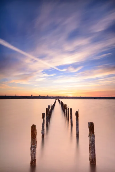 Stolpar i vattnet - på havet och solnedgången moln — Stockfoto