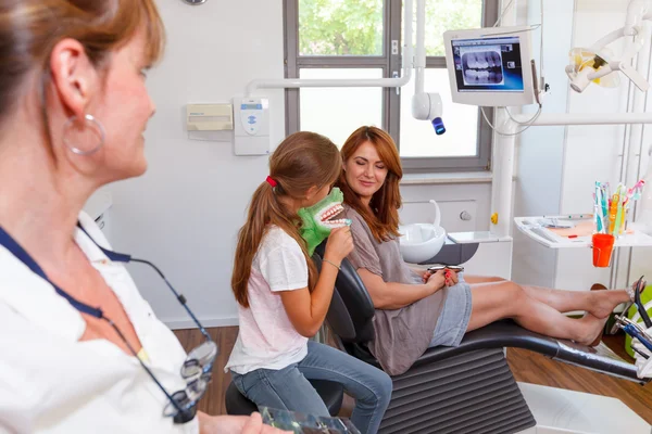 Un medico di odontoiatria sembra felice madre di famiglia un bambino su sfondo — Foto Stock