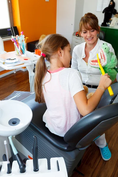 Uma dentista médico joga escovar os dentes com uma jovem — Fotografia de Stock