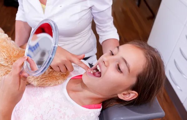 A doctor explains a young girl how she can care the teeth. — Stock Photo, Image