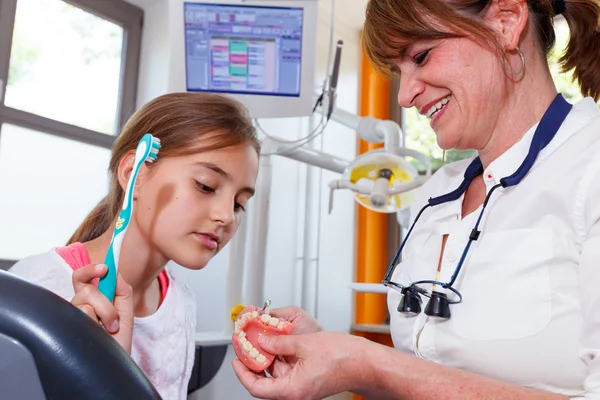 A doctor explains a young family how they can care the teeth — Stock Photo, Image