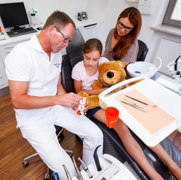 Un médico explica a una familia joven cómo la caries no es dios de los dientes — Foto de Stock