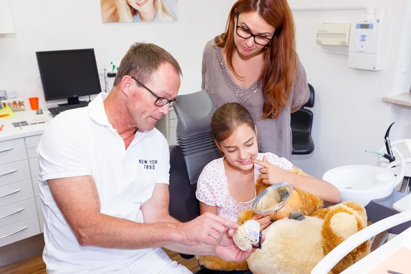 A doctor explains a young mother and douther how they can care teeth — Stock Photo, Image