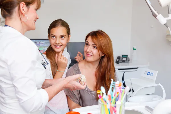 Un medico dei denti delle donne spiega una madre con un bambino come lavarsi i denti Immagini Stock Royalty Free