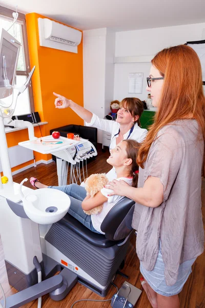 Un médico que muestra a una familia joven una imagen de rayos X en el monitor led Fotos De Stock