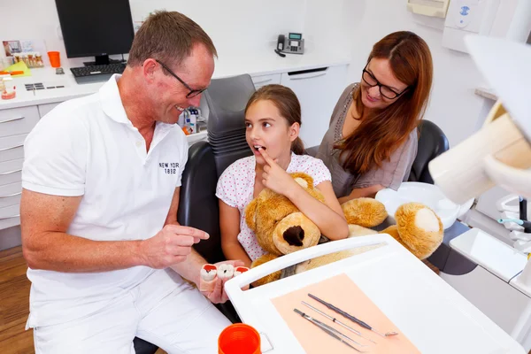 Un medico spiega una giovane famiglia, madre e adolescente ragazza, come la cura dei denti Foto Stock