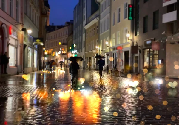 雨が降る雨の通り夜の人々が傘で歩く夜の光の反射舗装タリン旧市街中世都市エストニア — ストック写真