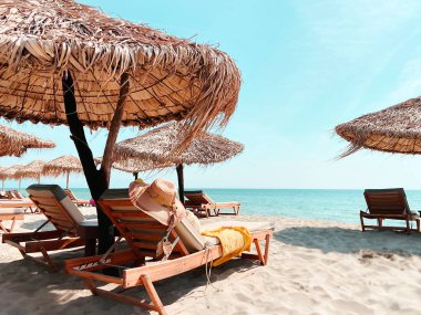 Beyaz kumsal kamışları şapka şapkaları şemsiyeler mavi gökyüzü ahşap masalar güneş dinlenme yerleri Akdeniz tropikal doğa beldesi Olympus Dağı Yunanistan Yaz Tatili