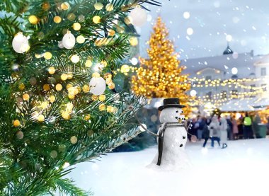 Yılbaşı ağacı dalındaki karlı adam, Tallinn Estonya 'da yeni yılı kutlayan kasaba meydanında karlı şenlikli bokeh ışığı yaktı.