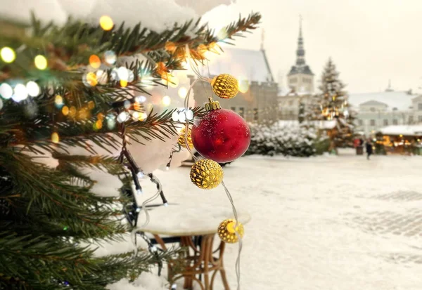 クリスマスツリー緑の枝赤いボール金のコンフェッティと雪の通り中世タリン旧市街の冬の天候につるとロマンチックなランタンキャンドルのガラスと黄色のガーランド照明 — ストック写真