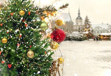 Noel ağacı yeşil dallı kırmızı top altın konfetisi ve sarı çelenk aydınlatması Tallinn 'deki eski kasabanın karlı havasında