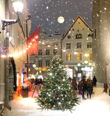 Ortaçağ şehir caddesinde akşam vakti aydınlatılmış Noel ağacı, vitrinlerde fener ışığı bulanık, gece gökyüzü dolunayı insanlar Tallinn 'deki eski kasaba meydanında karlı havada yürüyor. 