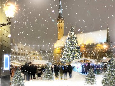  Snowy Christmas City Green tree illumination decoration on evening blurred light in medieval street in   old Tallinn old town hall square market place snow fall people  walk and celebration season  holiday travel to  Estonia Europe 
