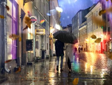 Autumn in city  romantic couple under umbrella in rainy evening city walk medieval stree blurred light light in Tallinn old town yellow leaves fall  rainy weather rain drops travel to Estonia Europe