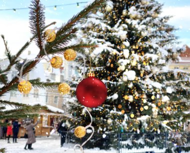 Noel ağacı kırmızısı top, Tallinn 'in eski kasabasındaki kasaba meydanında bokeh ışığını bulanıklaştırdı. Snopflacke üflüyor. İnsanlar yürüyor ve bayram bayramını kutluyorlar. 