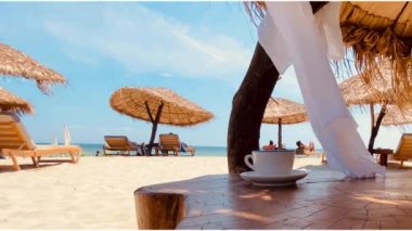 Yunanistan 'da kahve tatili masasında mavi deniz suyu, beyaz kum ve parazit.