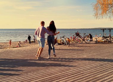   Günbatımında şehir güvertesinde dans eden insanlar Baltık Denizi 'nde