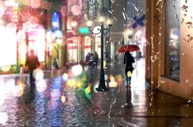  Yağmur şehri sonbahar akşamı şehir merkezinde gece ışığı neon yansıması ıslak kaldırımlara yağmur damlaları insanlar eski Tallinn kasabasında şemsiyelerle yürür.