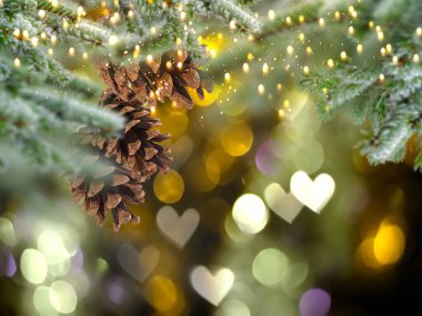 Christmas tree branch with cone and bokeh light heart sumbol gold bakcground template copy space