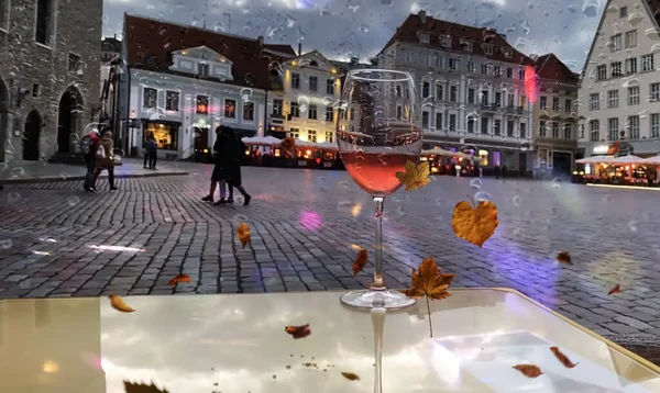 rainy Evening blurred light Autumn in Tallinn old town hall square street cafe rain drops on window glass of water ash berry and yellow leaves fall weather forecast season in Estonia
