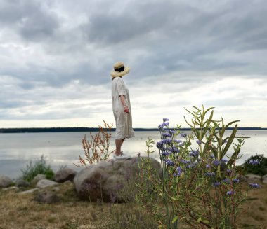   woman stay  at stone on  wild  beach and watching cloudy sky after storm