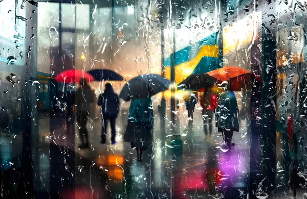 rainy city,rain drops on window evening rainy city ,people walk with umbrellas blurred light urban city weather forecast