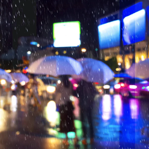 rainy street people with umbrellas walk blurred light shop windows reflection ciry  rain  urban life style