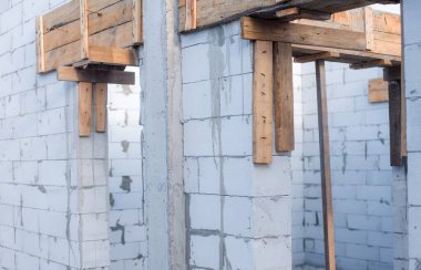 İnşaat halindeki bir evde havalanan bloklar. Beton zemini olan büyük beyaz bir ev.