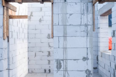 İnşaat halindeki bir evde havalanan bloklar. Beton zemini olan büyük beyaz bir ev.