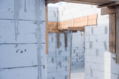 İnşaat halindeki bir evde havalanan bloklar. Beton zemini olan büyük beyaz bir ev.