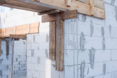 İnşaat halindeki bir evde havalanan bloklar. Beton zemini olan büyük beyaz bir ev.