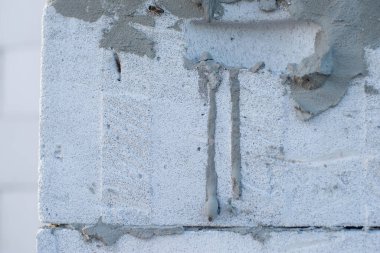 İnşaat halindeki bir evde havalanan bloklar. Beton zemini olan büyük beyaz bir ev.