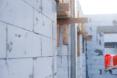 İnşaat halindeki bir evde havalanan bloklar. Beton zemini olan büyük beyaz bir ev.