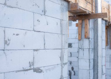 İnşaat halindeki bir evde havalanan bloklar. Beton zemini olan büyük beyaz bir ev.