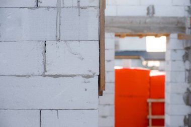 İnşaat halindeki bir evde havalanan bloklar. Beton zemini olan büyük beyaz bir ev.