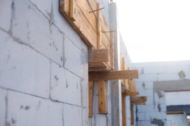 İnşaat halindeki bir evde havalanan bloklar. Beton zemini olan büyük beyaz bir ev.