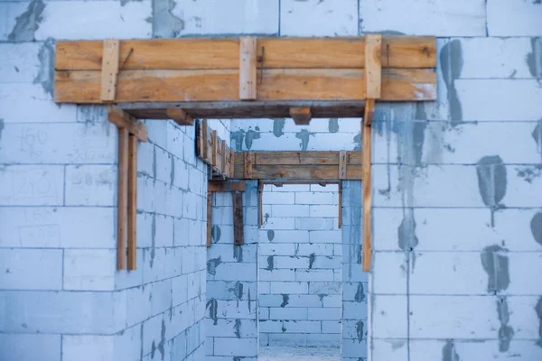 İnşaat halindeki bir evde havalanan bloklar. Beton zemini olan büyük beyaz bir ev.