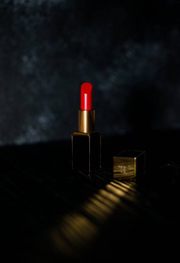 Koyu bir arka planda koyu sarı bir çantada kırmızı ruj.