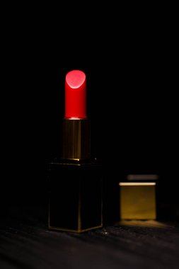 Koyu bir arka planda koyu sarı bir çantada kırmızı ruj.