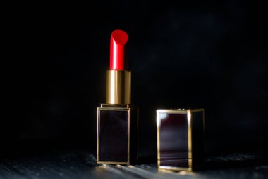 Koyu bir arka planda koyu sarı bir çantada kırmızı ruj.