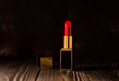 Koyu bir arka planda koyu sarı bir çantada kırmızı ruj.