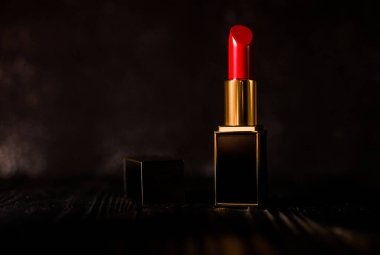 Koyu bir arka planda koyu sarı bir çantada kırmızı ruj.