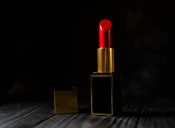 red lipstick in a dark gold case on a dark background