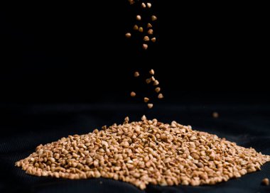 Bir elden çıkan karabuğday, yere düşen karabuğday lapası, arka planda bir dişinin elinde çiğ.