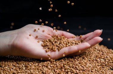 Bir elden çıkan karabuğday, yere düşen karabuğday lapası, arka planda bir dişinin elinde çiğ.