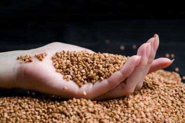 Bir elden çıkan karabuğday, yere düşen karabuğday lapası, arka planda bir dişinin elinde çiğ.