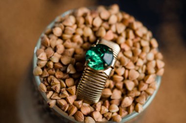 Karabuğday ve mücevher, bir yüzük ve arka planda çiğ karabuğday bileziği.